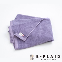 一條淺紫色、織有鱗紋的薄手浴巾，材質觸感柔軟，邊緣有同色系包邊，角落處縫有品牌標籤。