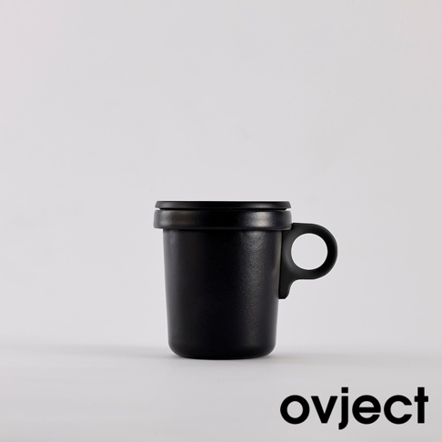 黑色琺瑯馬克杯，帶有圓形提把和黑色杯蓋，材質為金屬琺瑯，設計簡約。