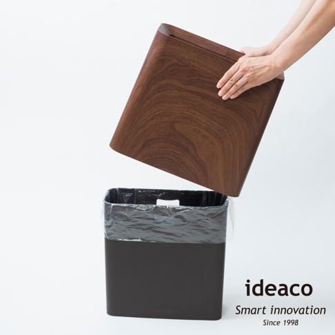 胡桃木紋方形家用垃圾桶，附有黑色內桶和透明垃圾袋，上方為可拆卸的胡桃木紋桶蓋，由雙手拿取。