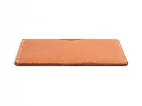 淺棕色皮革製成的簡約文件夾，邊緣有白色縫線，整體呈現長方形，一側邊緣有輕微的弧度。