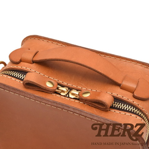 HERZ 職人手作皮革兩用迷你小方包，特寫箱包的拉鍊細節與皮革提把，日本手工製造 since1973