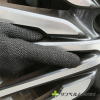 一隻深灰色網狀材質的清潔手套，覆蓋在汽車輪圈的細節處，展示其清潔能力。