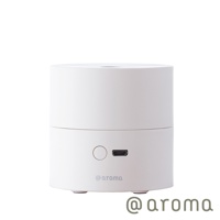 白色圓柱形隨身精油香氛機，頂部有出霧口，機身正面有電源開關按鈕和 USB 充電孔，底部有三個小支腳，整體為霧面材質。