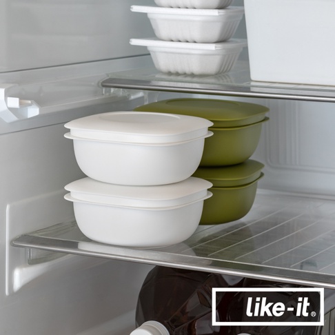 冰箱架上擺放著一組兩個白色簡約雙層蒸氣循環保鮮盒，堆疊整齊。右側還有兩組綠色同款保鮮盒。