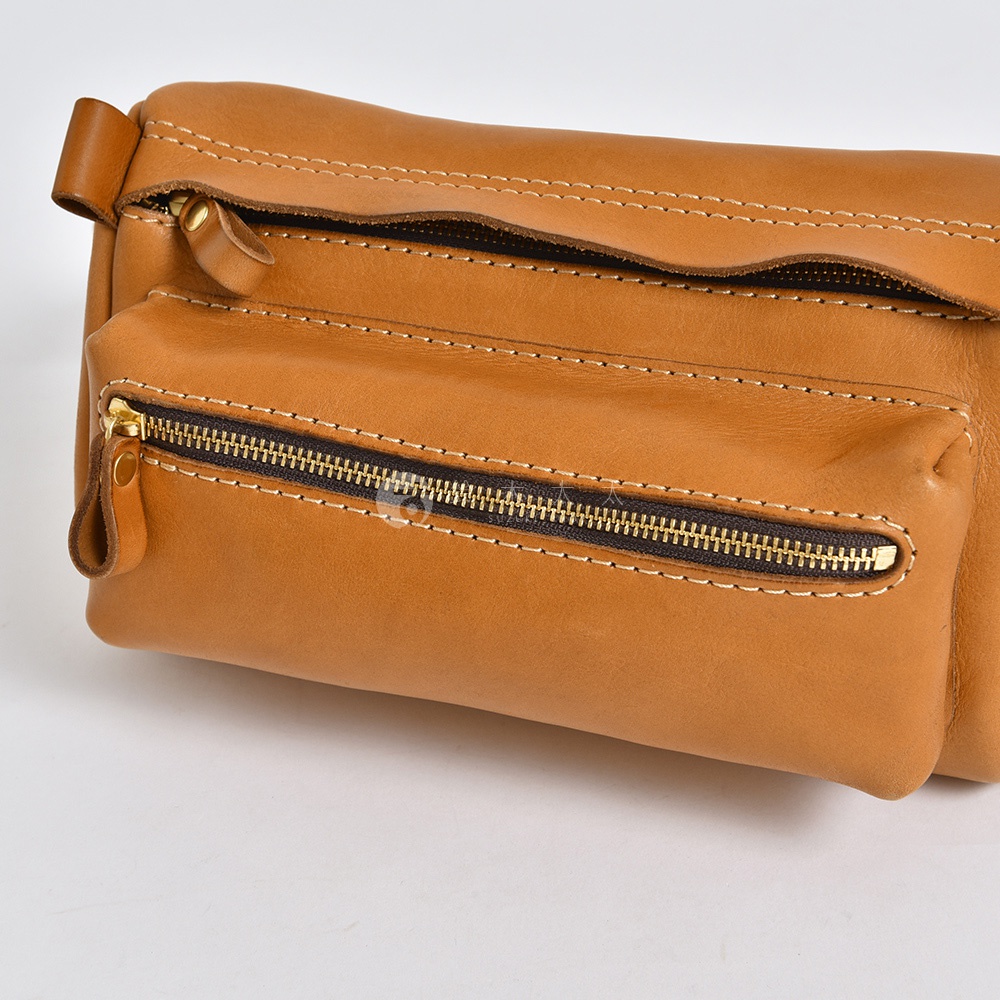 職人手作淺棕色皮革兩用腰掛斜背包，設有兩個拉鍊隔層，搭配金色拉鍊和咖啡色車線。