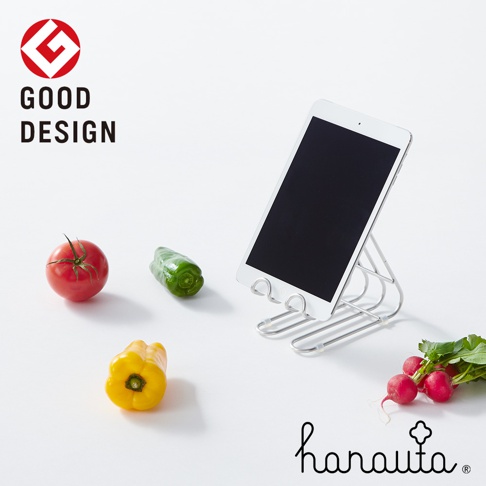 銀色不鏽鋼萬用支架，支撐著一台平板電腦，旁邊擺放著番茄、青椒、黃甜椒和櫻桃蘿蔔。