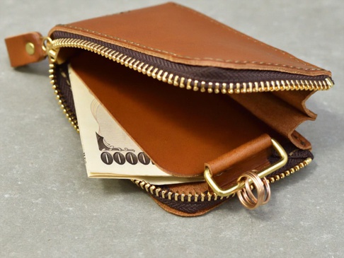 一個棕色皮革製成的拉鍊式卡片鑰匙包，內部有卡片和鑰匙圈。