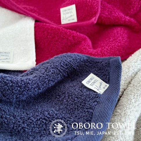 摩登復古風細纖毛巾，特寫展示深藍、桃紅、白色及淺灰色毛巾堆疊。毛巾材質柔軟，織紋細緻，角落有品牌標籤。