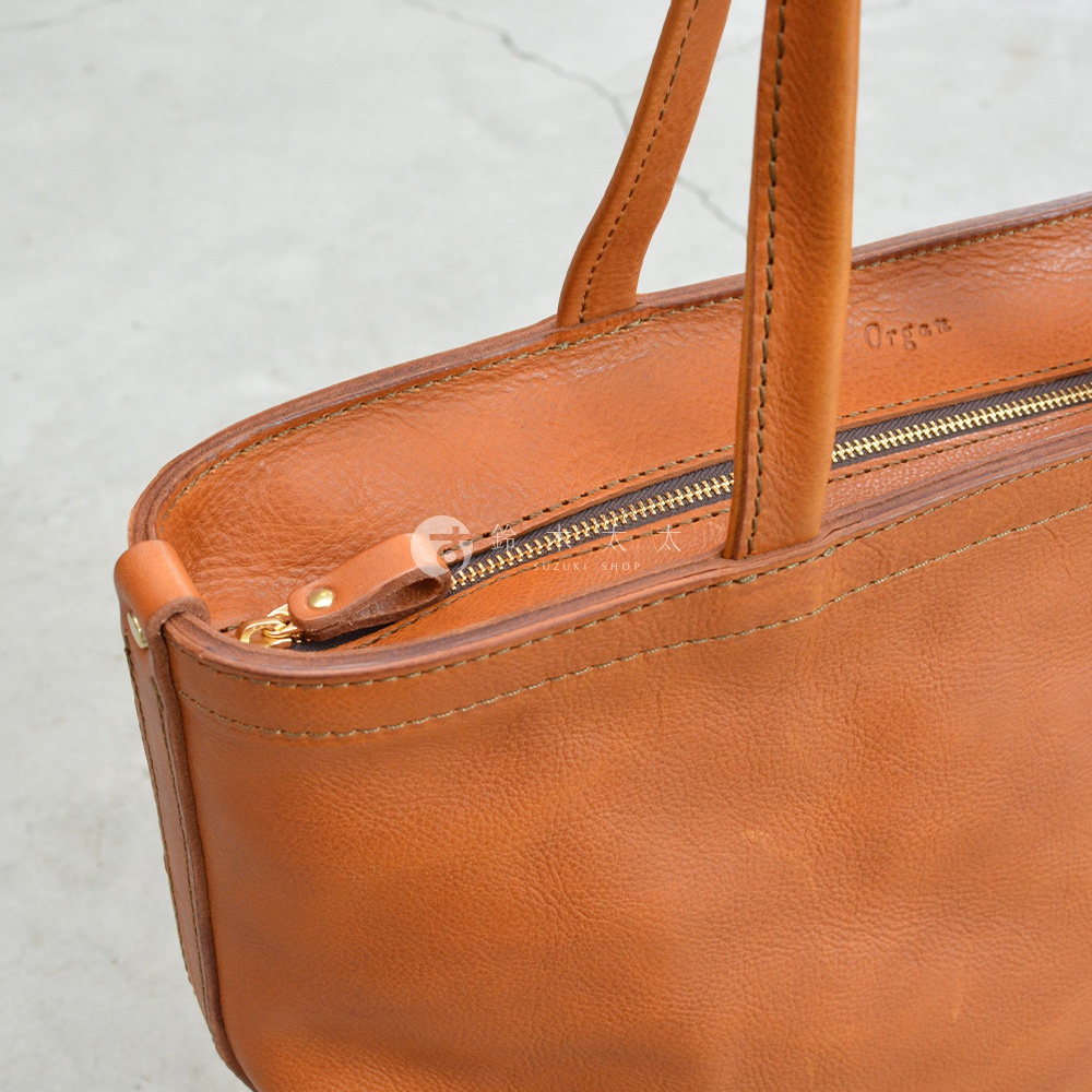 職人手作Organ品牌皮革製成的棕色托特包，特寫拉鍊細節與縫線，展現皮革的自然紋理。