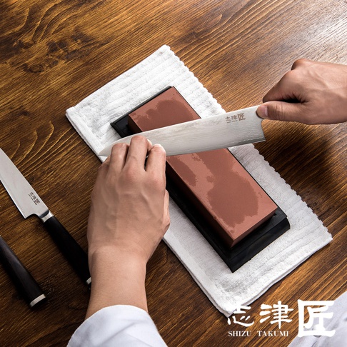 男人正在使用志津匠磨刀石打磨一把武士刀。