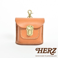 淺棕色皮革製作的耳機收納包，有翻蓋和金屬鎖扣，頂部有金屬掛鉤，整體風格簡約，展現職人手作質感。