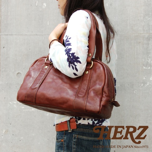 職人手作皮革水洗加工迷你波士頓包，採用棕色皮革製成，包身呈現自然的紋理與光澤，配有雙提把和金色五金配件。