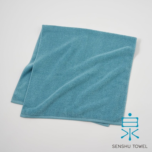 一張藍綠色長纖迷你浴巾，材質柔軟，邊緣有細緻包邊，右下角有「泉 SENSYU TOWEL」的品牌標誌。