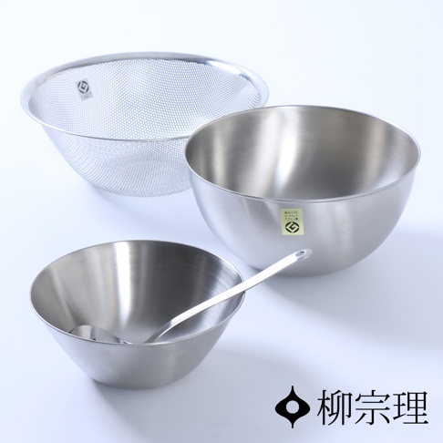 不鏽鋼調理盆組，包含一個帶有細密網孔的不鏽鋼瀝水籃，以及兩個不同尺寸的不鏽鋼調理盆，其中一個盆內放有一支不鏽鋼湯勺。