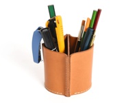 淺棕色皮革製的雙隔筆筒，內含藍色釘書機、黑色簽字筆、黃色美工刀、綠色和紅色鉛筆、畫筆及其他文具。