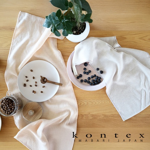 MOKU ORGANIC 有機棉長毛巾，一條為淺粉色，另一條為米白色，鋪在木質桌面。淺粉色毛巾一旁擺放著裝有咖啡豆的玻璃罐和白色盤子，盤上有咖啡豆及木勺。米白色毛巾蓋在裝有藍莓的淺粉色盤子上。