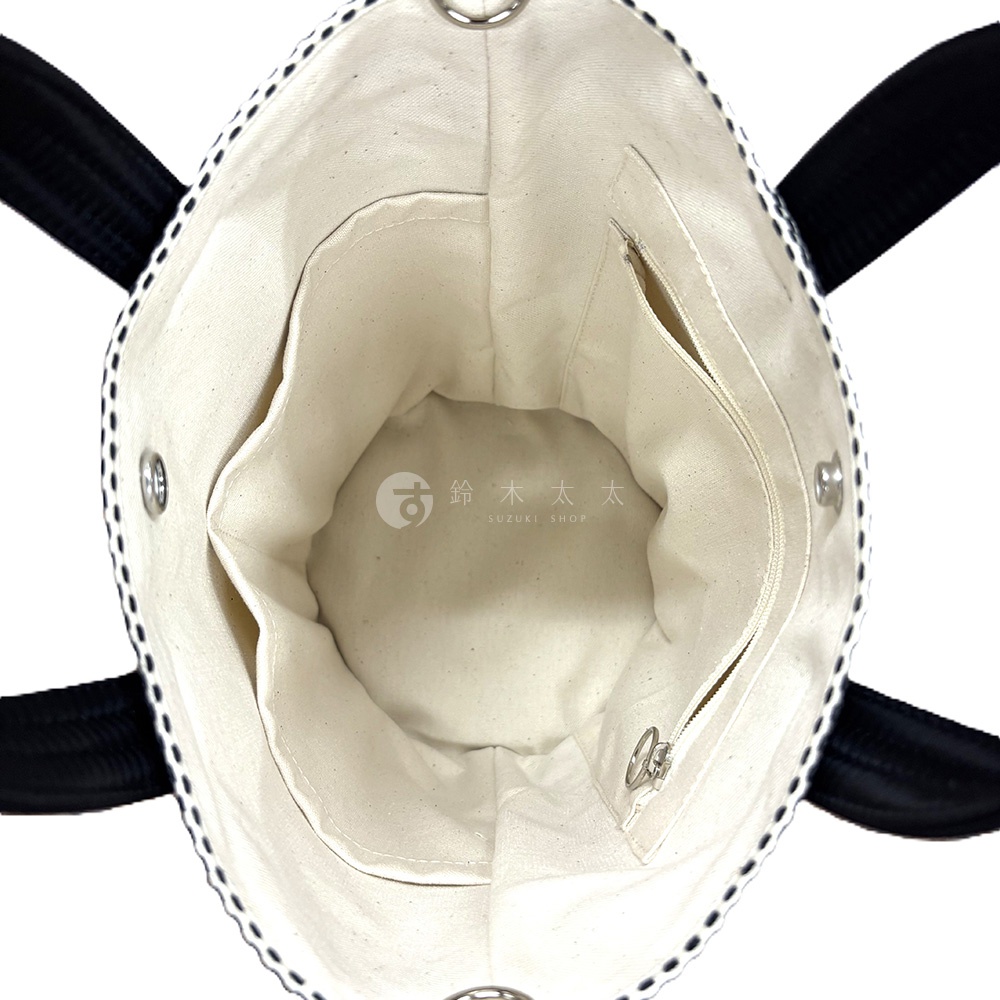 三河木綿刺子織兩用水桶包內部，米白色帆布內襯，有兩個開放式內袋和一個拉鍊內袋，黑色提把，包緣有黑色刺繡裝飾。