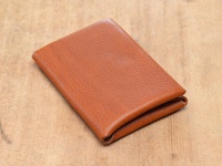 職人手作皮革Organ雙開卡片收納夾，呈現焦糖棕色，材質為紋理皮革，雙折設計，置於木紋背景上。