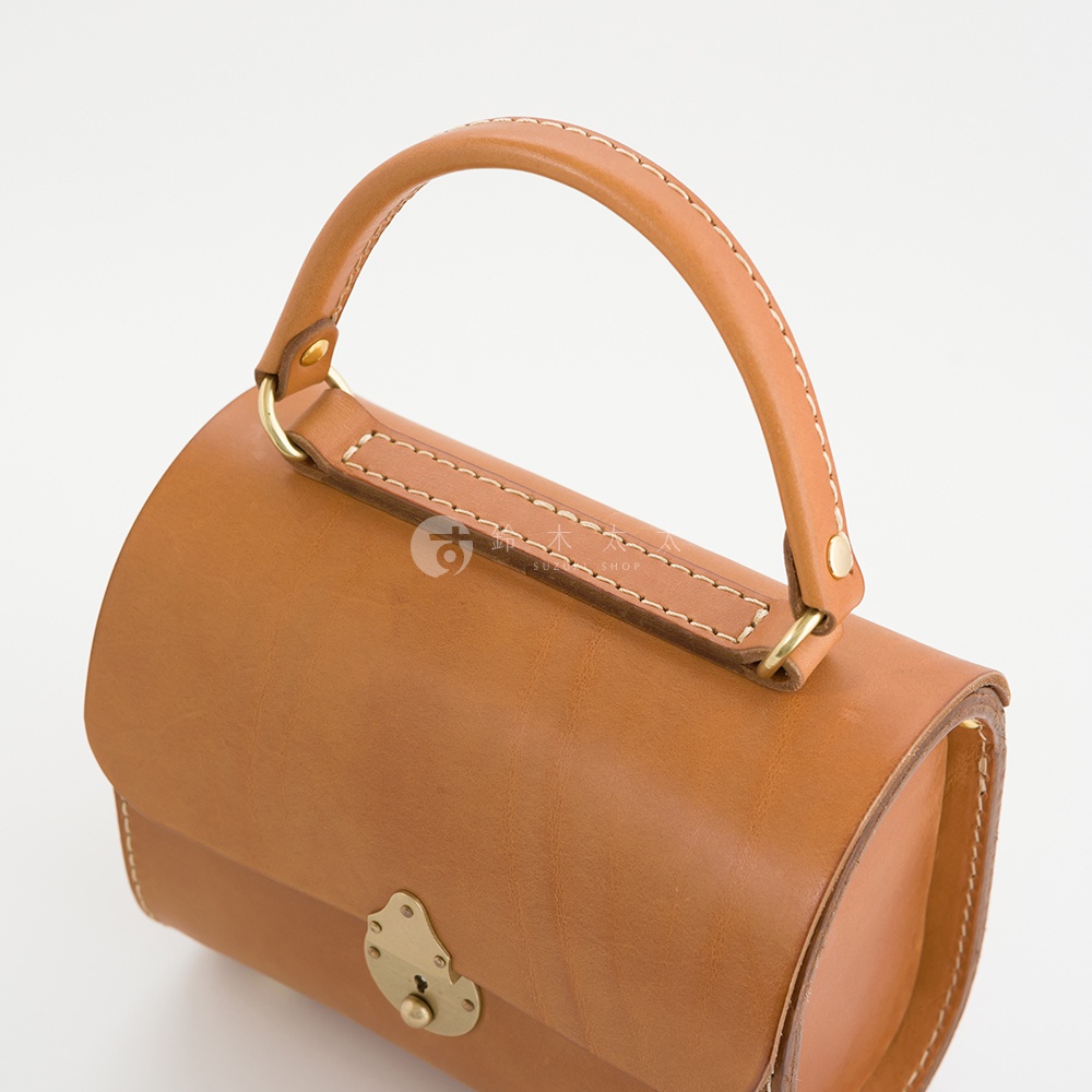 職人手作皮革復古杜勒斯手提包，採用天然棕色皮革，搭配黃銅色金屬鎖扣與提把，整體呈現簡約復古風格。