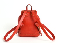 職人手作紅色皮革迷你後背包，採用圓潤桶狀設計，搭配可調式皮革肩帶和金色扣環，展現經典復古風格。