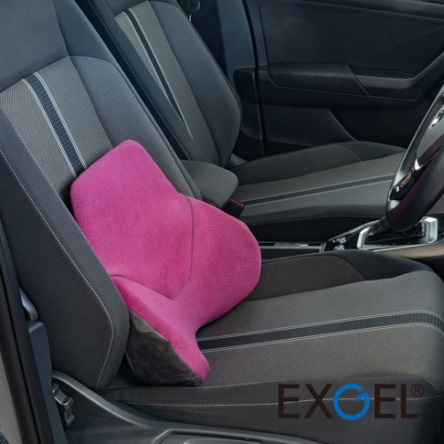 一張日本EXGEL汽車用一體式麂皮背靠墊放置在深灰色汽車駕駛座上，粉紅色的背靠墊採人體工學設計，呈現出優雅的曲線弧度，表面材質為細緻的麂皮，整體質感舒適且現代。