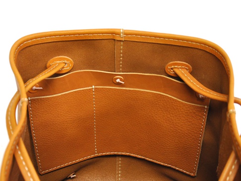 職人手作皮革兩用大容量托特包內部特寫，呈現焦糖色皮革，有兩個開放式內袋，縫線清晰，附有皮革抽繩。