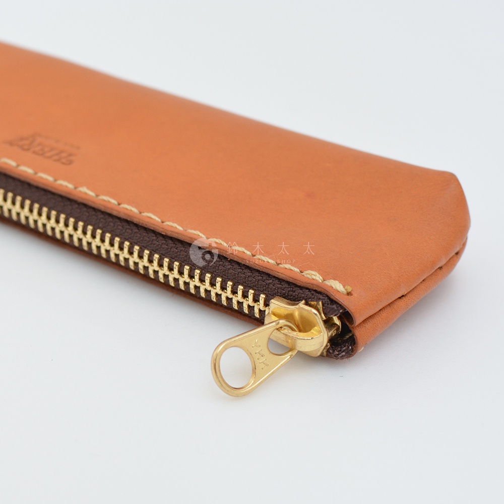 職人手作皮革經典收納筆袋，展示卡其色皮革與金色拉鍊，皮革表面有壓印 Logo，縫線精緻，整體呈現簡約經典風格。