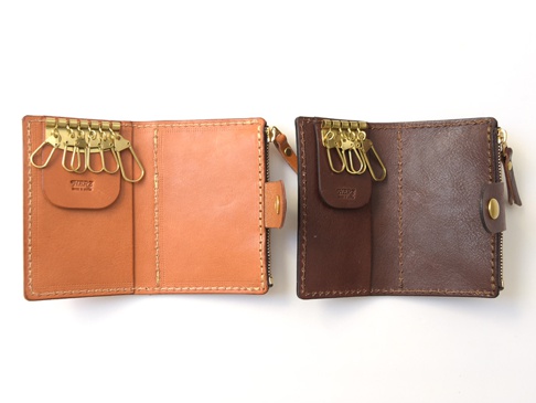 展示兩個職人手作皮革拉鍊零錢鑰匙包，一個為淺棕色，另一個為深棕色。兩款皆為開放式設計，內有六個金色鑰匙鉤，並壓印有「HERZ MADE IN JAPAN」標誌。