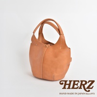 一款 tan 色皮革製成的球形肩掛托特包，包身線條流暢，採用縫線設計，配有雙提把，整體風格簡約。