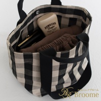 黑白格紋帆布托特包，內有防曬乳、化妝包及棕色衣物，設計簡約實用。