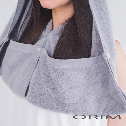 淺灰色毛巾布質地的吹髮頭巾，採用柔軟吸水材質，設計有兩個口袋，透過按扣固定，適合包裹濕髮。