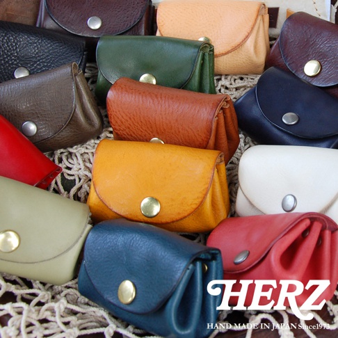 多個職人手作皮革零錢包，顏色包含紅、深棕、綠、橘黃、深藍、米白、淺綠、深紅、淺棕，皆為真皮材質，附有金屬按鈕。