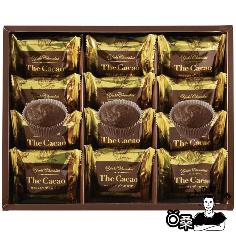 烤巧克力菓子禮盒，內含十二個獨立包裝的巧克力菓子，每個菓子為深棕色，置於白色杯狀包裝內，外層包裝為金色與深棕色，印有「Yaki Chocolat The Cacao」字樣。