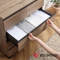 附櫃腳木製收納櫃，展示其中兩個抽屜，抽屜內整齊擺放著白色和淺灰色的衣物。收納櫃為木紋材質，搭配黑色嵌入式把手。