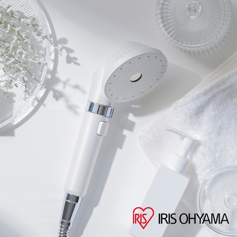 IRIS OHYAMA MICOLA 超微細泡蓮蓬頭，搭配白色方形壓瓶裝沐浴乳，以及白色毛巾和裝飾綠葉，呈現簡潔乾淨的浴室場景。