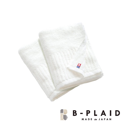 兩條白色純棉毛巾，表面有直條紋理，其中一條毛巾角落繡有「B-PLAID」品牌標誌，標誌由紅、藍、白色塊組成。