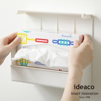 白色ABS材質的壁掛/桌上兩用擦手紙架，架上裝有印有彩色圖案的擦手紙盒，紙盒下方露出白色擦手紙。