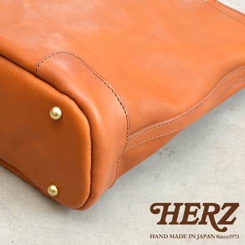 日本HERZ手工皮革托特包的底部細節，可見金屬腳釘與精緻縫線。