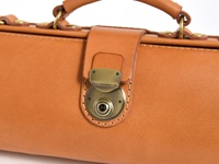 職人手作皮革橫長形單肩包，採用溫潤的棕褐色皮革，搭配復古黃銅色金屬鎖扣和鉚釘，整體呈現經典質感。