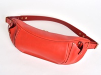 紅色皮革製成的大容量斜背包，具有彎月形輪廓，正面有金色拉鍊，側邊有兩個小皮帶環和可調節的紅色皮革背帶，帶有金色金屬扣環。