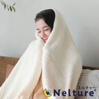 一名女子被一條奶油色、帶有紋理的柔暖毛毯包裹，毛毯材質看起來蓬鬆舒適，可見細緻的條紋紋路，營造溫馨居家氛圍。