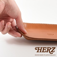 職人手作皮革小物收納盤，淺棕色皮革，邊緣縫線整齊，表面光滑，品牌標誌烙印其上。