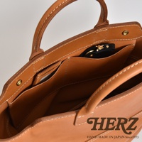 職人手作皮革大容量兩用托特包 T-8，呈現原色皮革質感，內部有卡片夾層與拉鍊小包，縫線清晰，設計簡約實用。