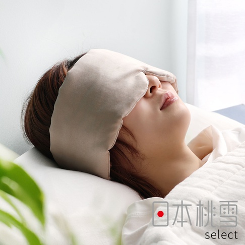 一位女性正側躺在白色枕頭上休息，配戴著一款觸感柔滑的香檳色絲綢眼罩，眼罩完美貼合臉部輪廓，營造出寧靜舒適的居家睡眠氛圍，圖片右下角標示著日本桃雪 select 的品牌資訊。