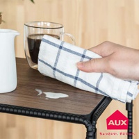 BOW 廚房工業風單層置物架-小，木紋檯面，黑色金屬支架。檯面上有一灘牛奶，一隻手正用藍白格紋抹布擦拭。