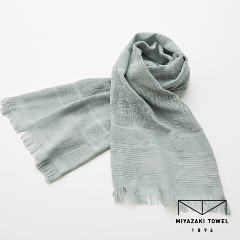 一條淺灰綠色的今治匹馬棉圍巾，帶有不同寬度的條紋織紋和流蘇邊緣，圍巾部分纏繞成圈。