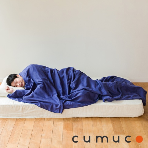 一位男性仰臥在床墊上，蓋著一件深藍色的四層紗輕暖舒柔四季毯。毯子材質柔軟，有自然的皺褶，覆蓋了大部分身體。