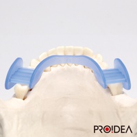 淺藍色靜音牙套，由半透明的矽膠材質製成，呈U型設計，兩側有圓形翼狀支撐，置於牙齒模型上，用於展示產品功能。