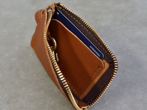 職人手作皮革Organ抽繩收納鑰匙包，焦糖棕色，拉鍊開合，內有鑰匙圈和可插卡夾層，細節展現皮革質感。