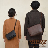 兩位模特展示了不同尺寸和顏色的皮革斜背包，分別為黑色和深棕色，展現了商品的實用性和風格。